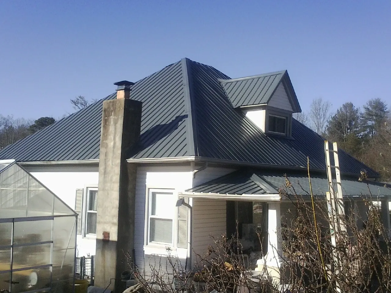 Dark blue standing seam metal roof on a white farmhouse with dormer — Slate & Tile Roof Repair by Roofing Brothers in Cassoday