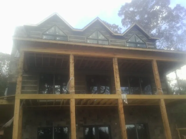 Dormers and porch framing on a large log home under construction — Roof Coating work by our crew in Cassoday
