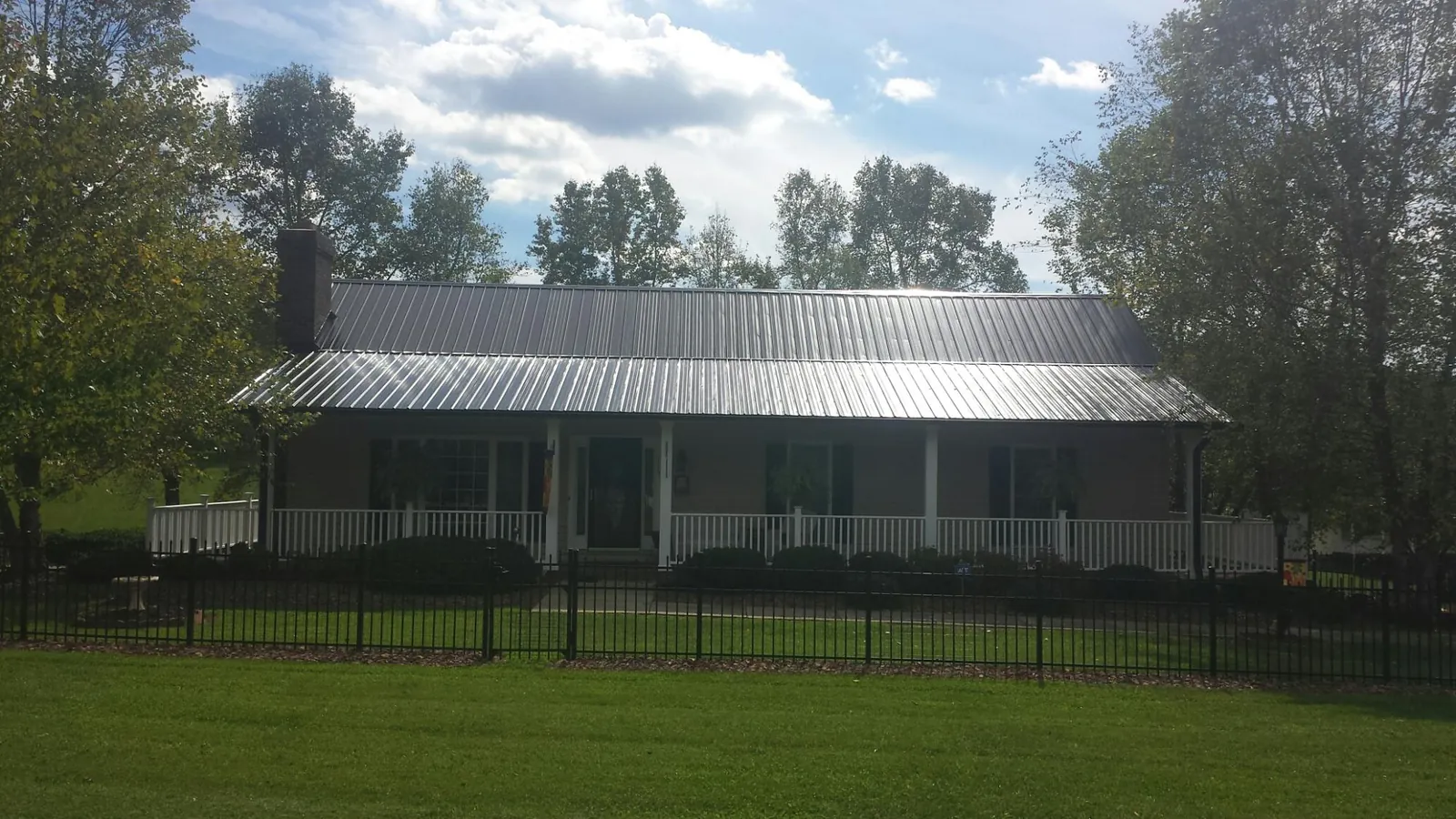 Gray metal roof on a brick ranch with a full width front porch — Gutter Guard Installation work by our crew in Cassoday