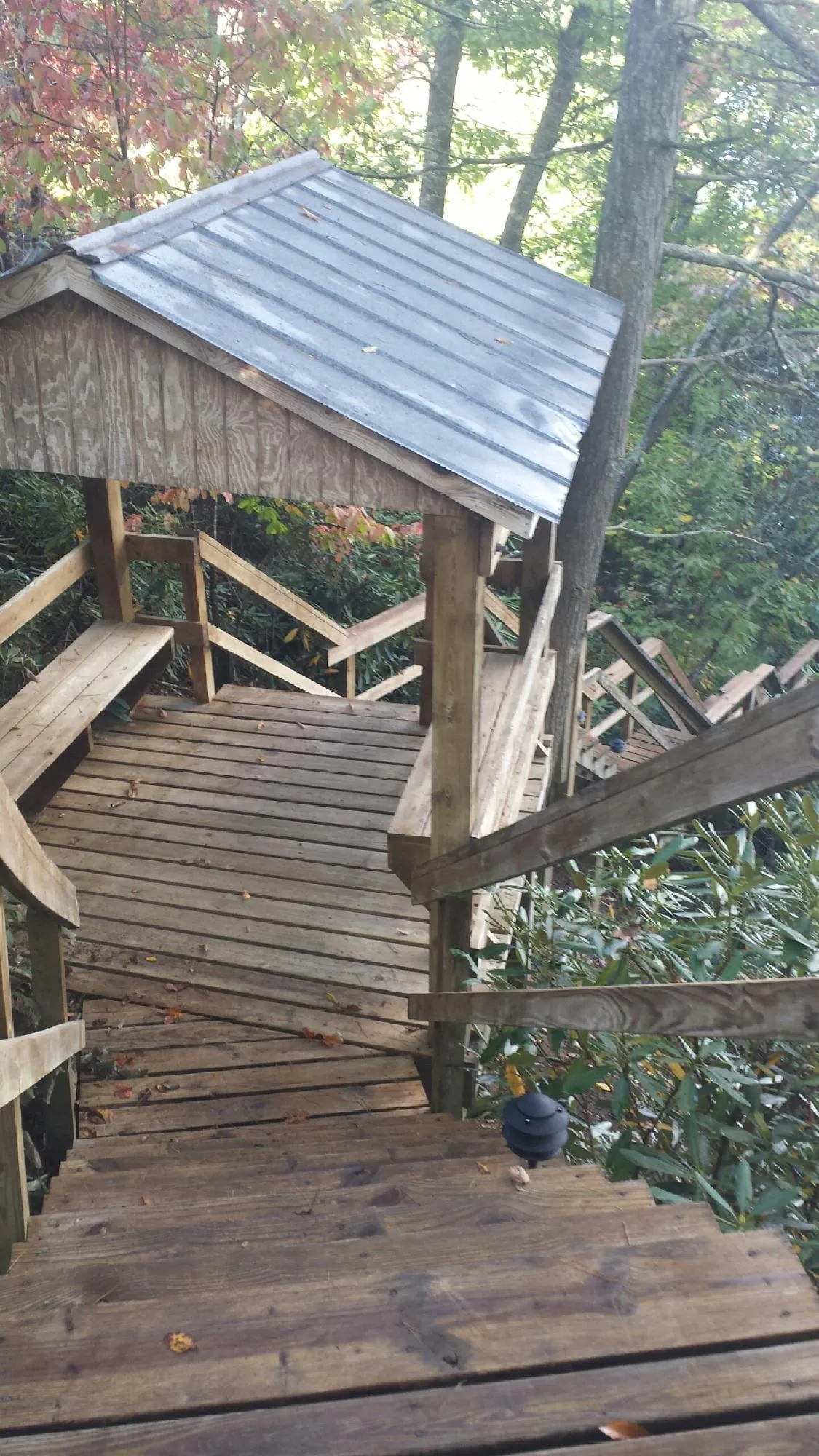 Metal roofed shelter over wooden steps on a wooded walkway — Skylight Repair & Installation work by our crew in Cassoday