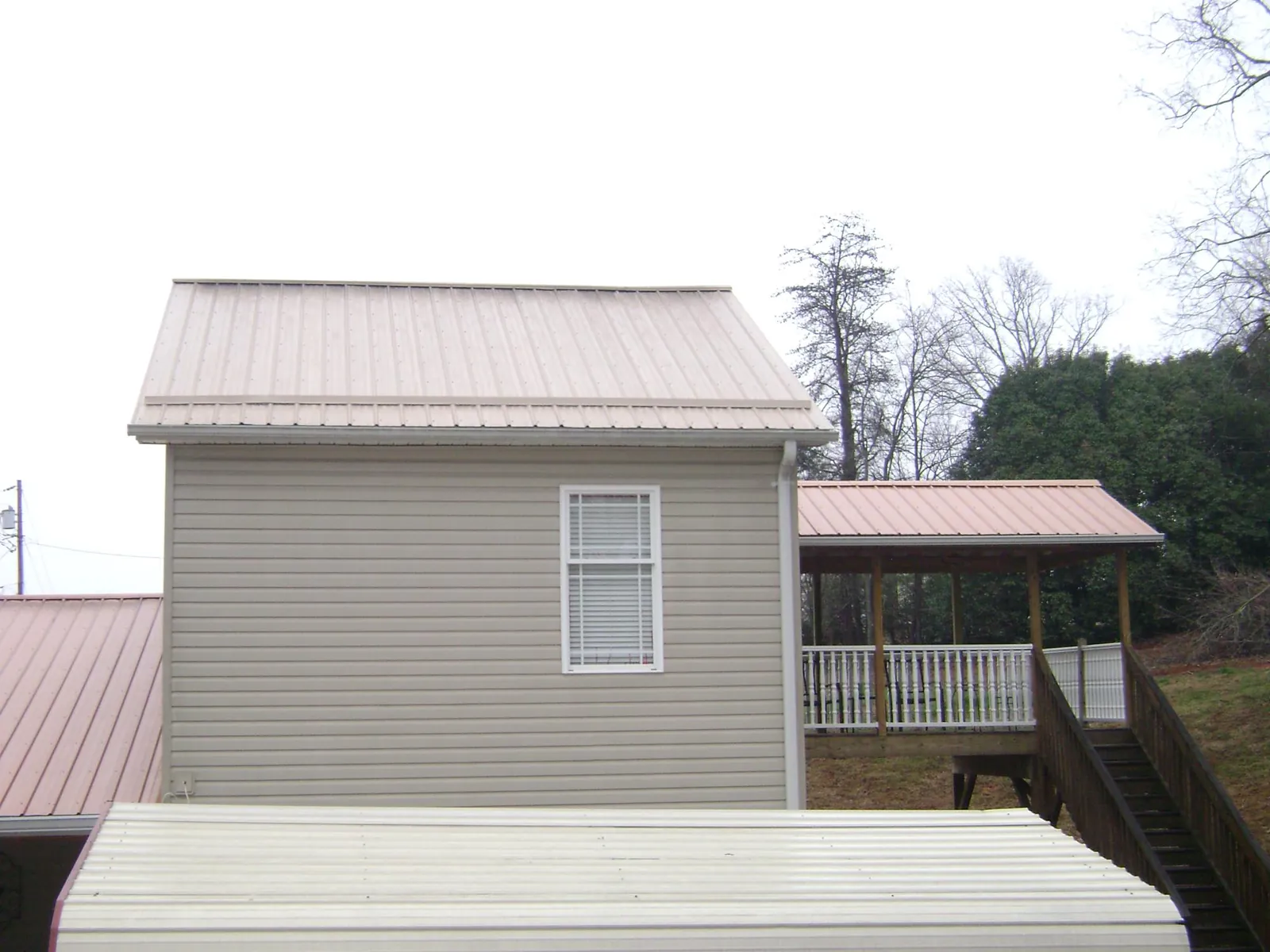 Tan metal roofs on a two story addition and attached porch, from a Roof Replacement job in Cassoday
