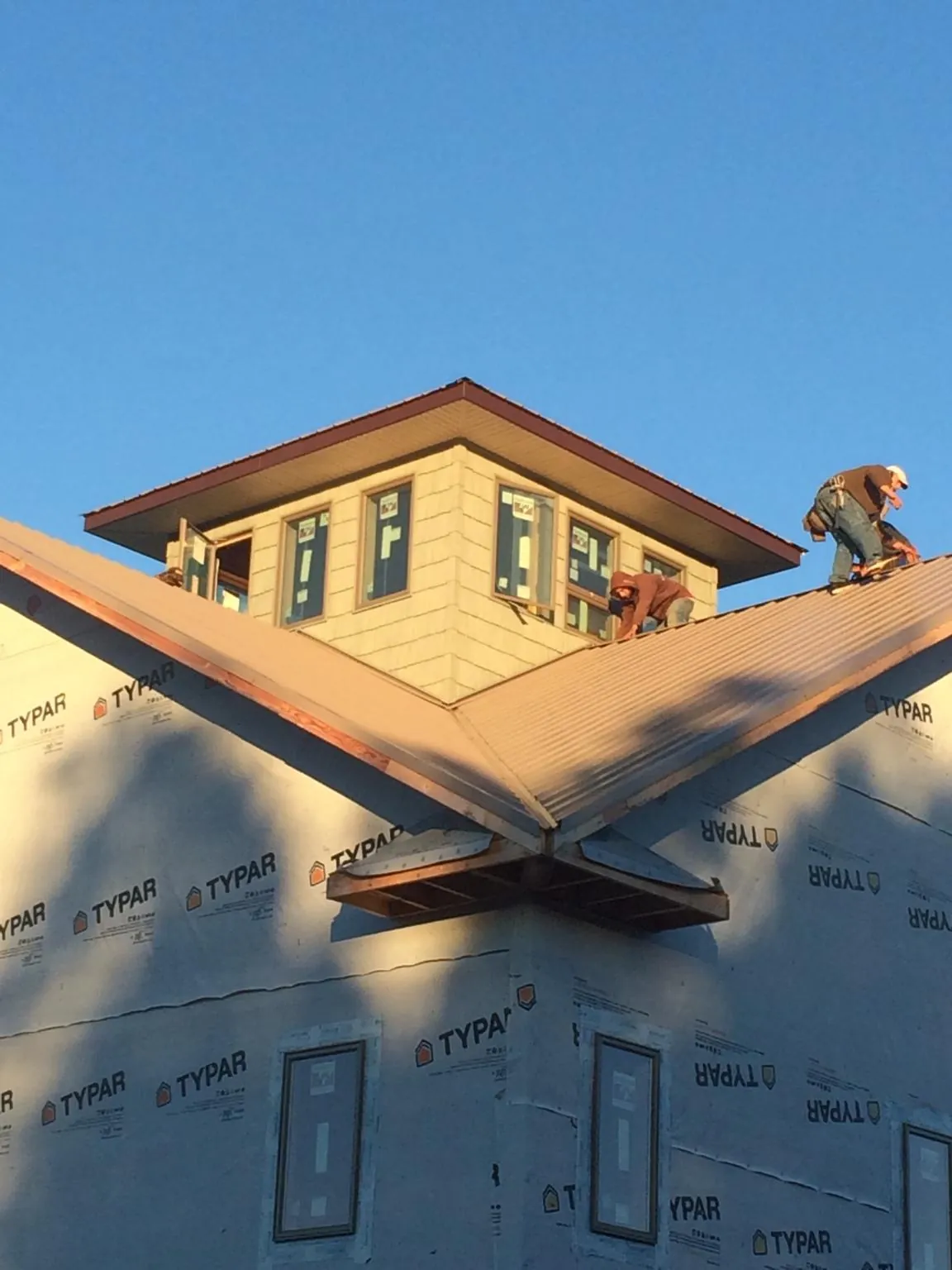 Roofers working around a rooftop cupola on a new metal roof at sunset — Roof Waterproofing in Cassoday by Roofing Brothers